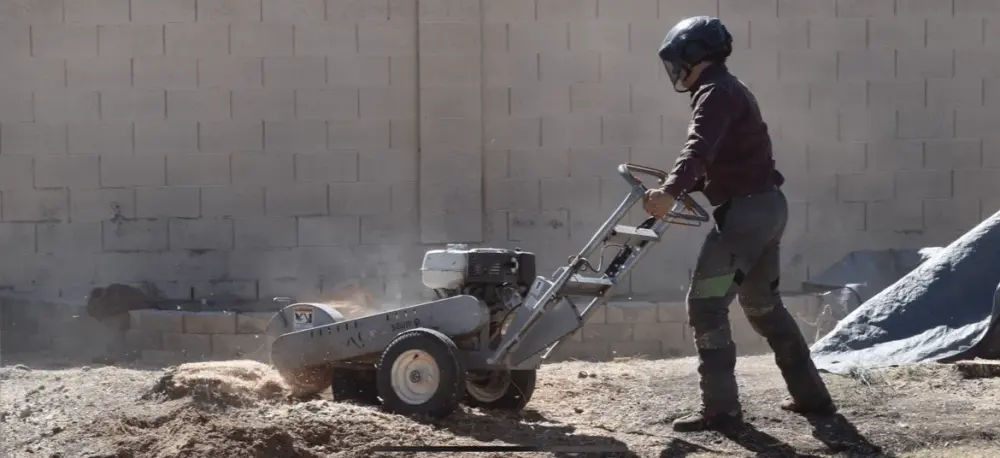 Crew member operating a stump grinder